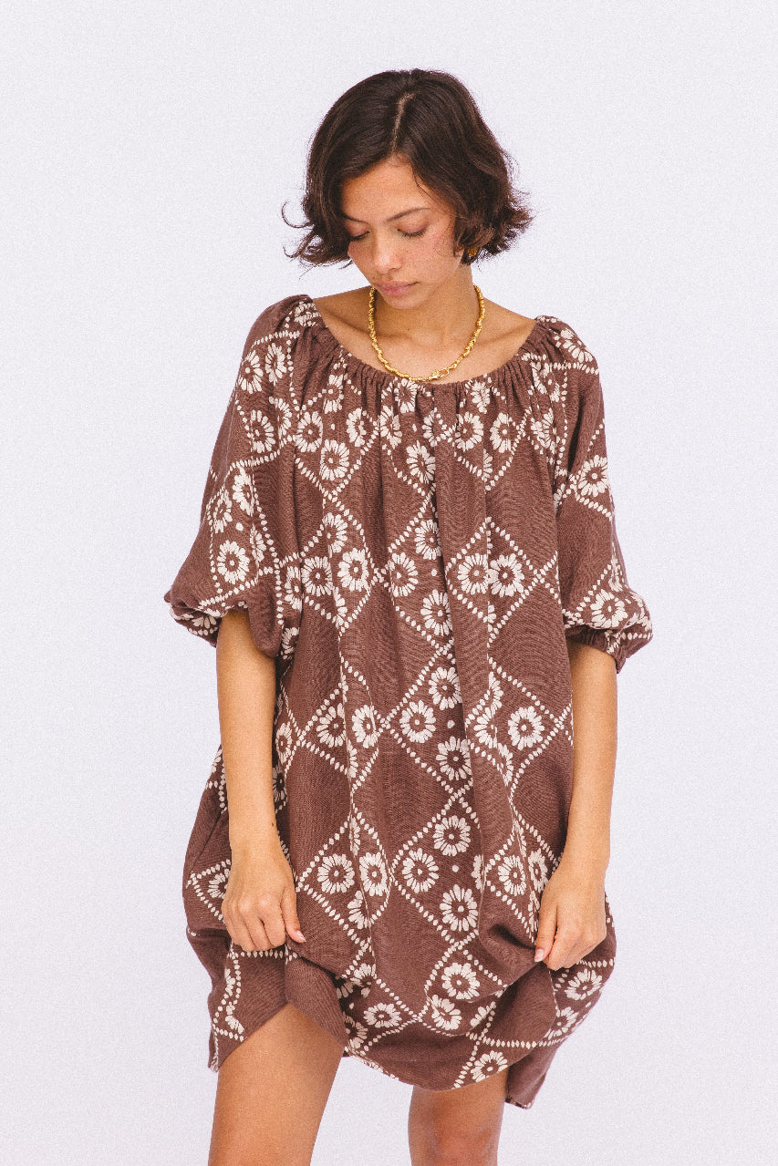 Dahlia Mini Dress Maple — studio model looking down, on-shoulder neckline, full front view of hand block print linen mini, maple brown diamond daisy motif, ethical boho dress Jaipur | Daughters of India