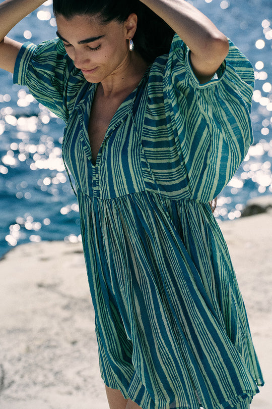 Woman wearing a green and blue striped dress by the water.