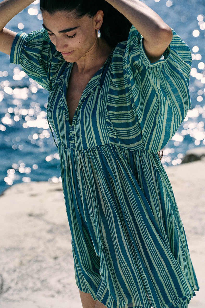 Woman wearing a green and blue striped dress by the water.